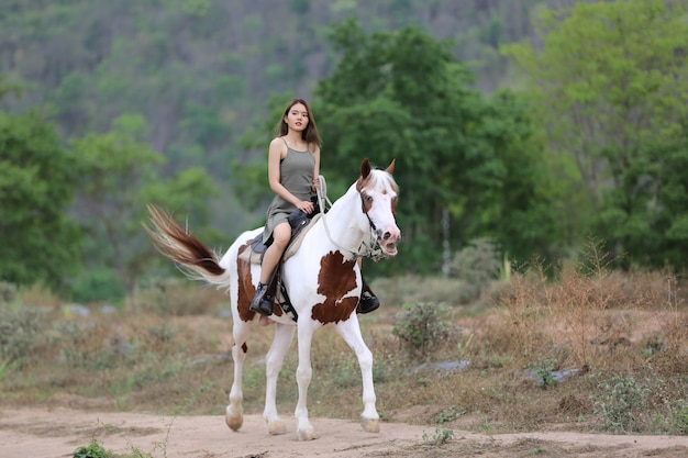 La longitud total de la mujer a caballo en el campo por árboles contra el cielo.