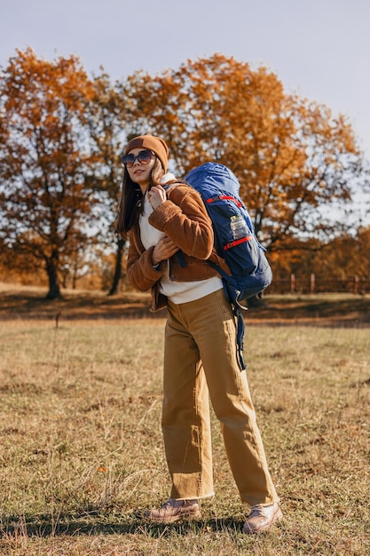 Longitud total de mujer viajera con mochila disfrutando de la aventura en otoño en la naturaleza