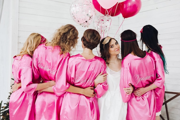 Foto longitud total de novia en túnica blanca con damas de honor de pie bac