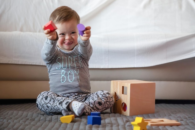 Longitude completa de menino feliz com síndrome de Down brincando no tapete em casa
