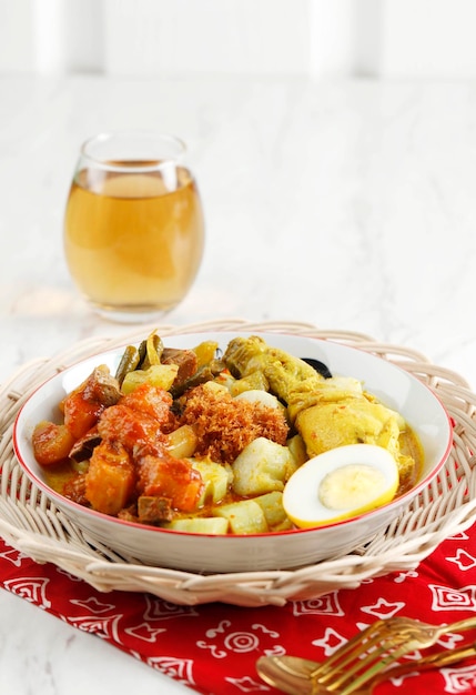 Lontong Cap Go Meh Indonesischer Lontong Sayur mit chinesischem Peranakan-Einfluss, serviert mit Tee