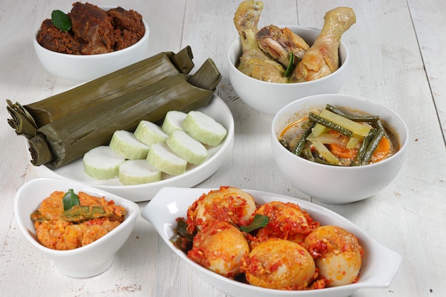 Lontong Lebaran servido com sambal goreng opor ayam sayur labu siam rendang e telur balado