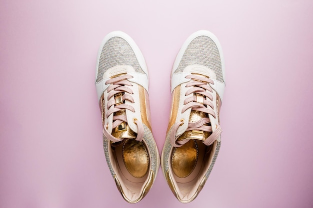 Foto look de blog de moda. zapatillas de mujer blancas con color rosa y dorado sobre fondo rosa. fondo femenino de la belleza de la vista plana endecha, superior.