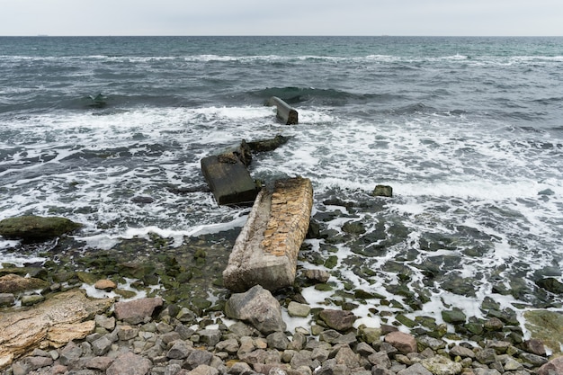 Foto losas de concreto rotas en la costa rocosa