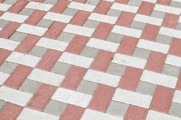 Losas o piedras de pavimento gris y rojo recién colocadas o pavimentadas para suelos o pasarelas. Losas de pavimento de hormigón en el patio trasero o pavimentación de carreteras. Camino de ladrillos de jardín en el patio sobre una base arenosa.