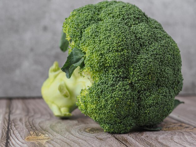 Foto loseup von frischem und rohem brokkoli auf holztisch und grauem hintergrund gesundes und vegetarisches essen