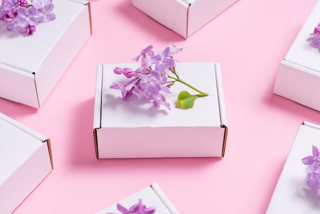 Lote de cajas de regalo decoradas con flores lilas en mesa rosa