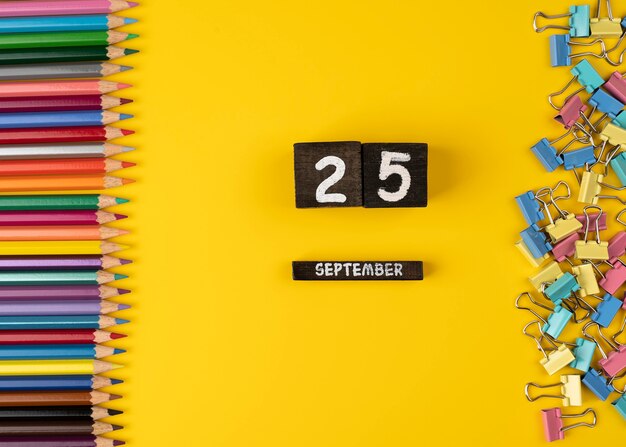 Lote de lápiz de color sobre fondo amarillo con fecha del 25 de septiembre calendario de madera