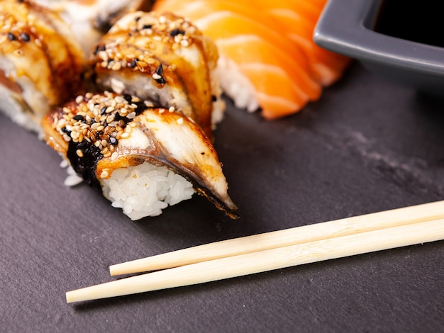 Lote mezcla variedad de rollos de sushi sobre fondo de piedra negra en foto de estudio