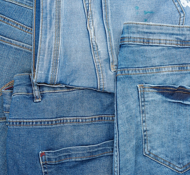 Lotes de jeans clássicos azuis empilhados caoticamente, bolso traseiro