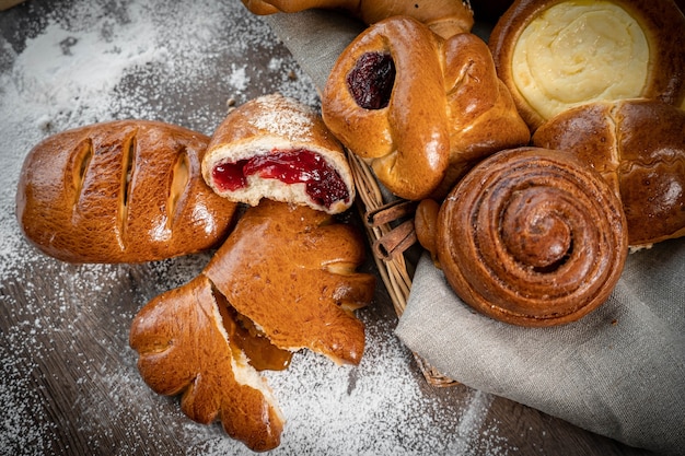 Lotes de pão fresco em uma cesta e uma tábua com farinha em uma mesa de madeira em estilo vintage rústico