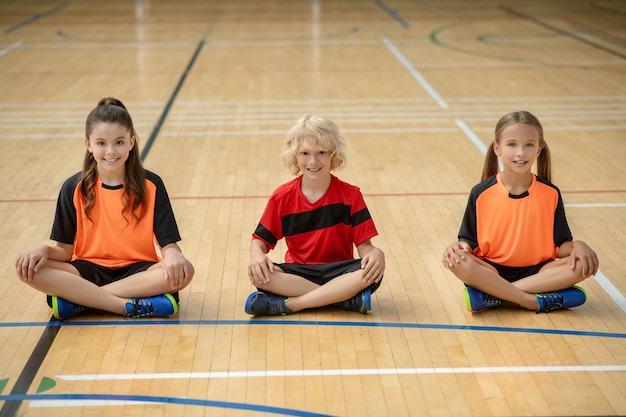 Lotus Pose. Kinder in heller Sportbekleidung sitzen im Lotussitz