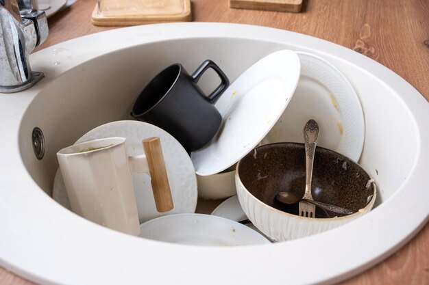 Louça suja na pia da cozinha bagunça depois do almoço com preguiça de lavar a louça Detergente para limpeza de cozinha Serviços de limpeza