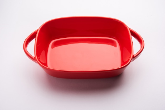 Louça vazia - tigela de cerâmica vermelha ou assadeira sem comida na superfície branca