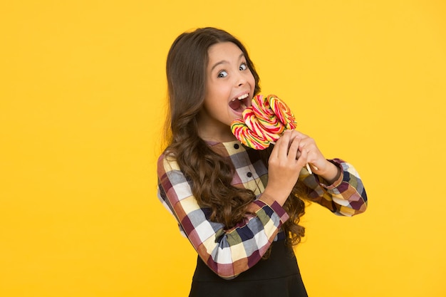 Louco por doces Vício em açúcar Criança feliz com doce doce Criança criança segurando pirulitos doces fundo amarelo Quebrando dieta Criança feliz com doces Nutrição escolar Calorias e energia