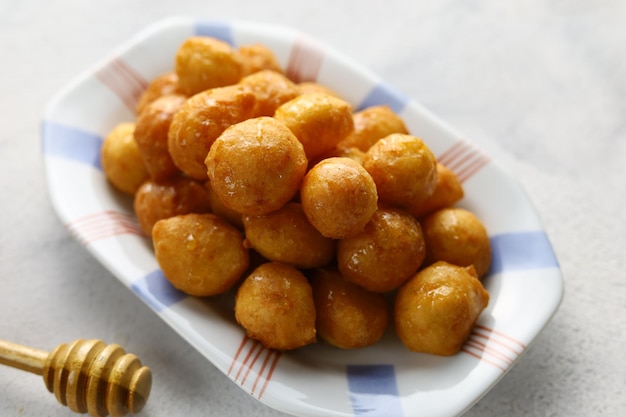 Loukoumades luqaimat o lokma con salsa de miel en un plato de fondo blanco