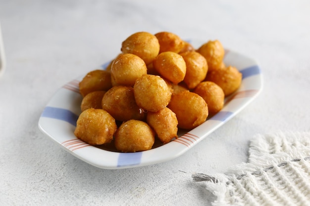 Loukoumades luqaimat o lokma con salsa de miel en un plato de fondo blanco