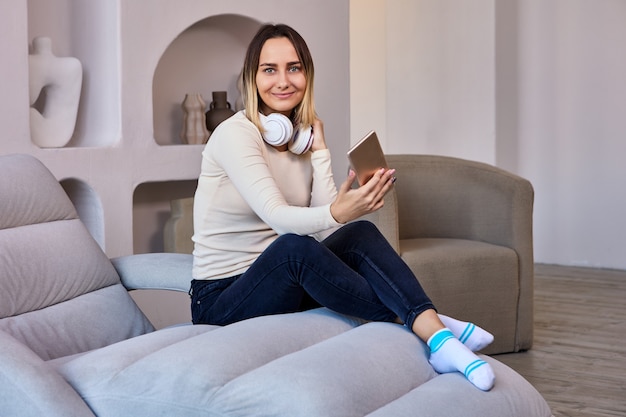 Lounge onde a mulher no sofá e com fones de ouvido segura o telefone