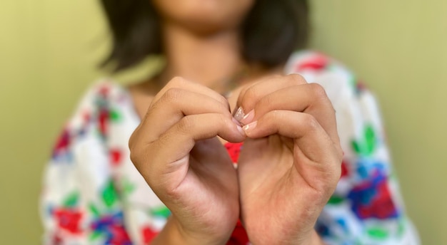 Love Sign feito à mão por uma mulher parece borrão usando camisa floral