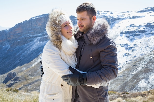Loving casal em jaquetas contra a serra nevada