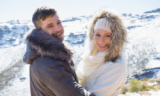 Loving couple em jaquetas em frente à montanha nevada