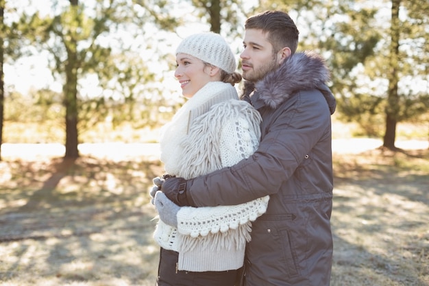 Loving jovem casal em roupas de inverno na floresta