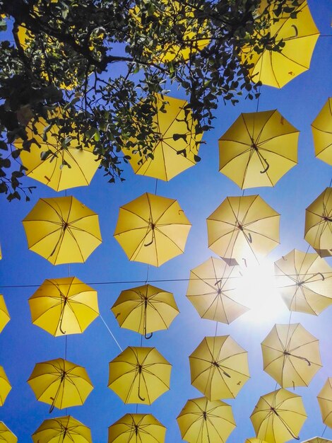 Foto low-angle-ansicht von gelben regenschirmen, die gegen einen klaren blauen himmel hängen