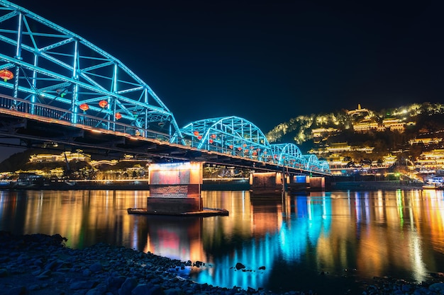 Low-Angle-Aufnahme einer beleuchteten blauen Brücke über Wasser in Lanzhou, China