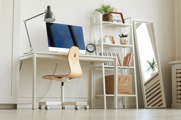 Low Angle View am rein weißen Home-Office-Arbeitsplatz mit Holzstuhl und modernem Computer auf dem Schreibtisch