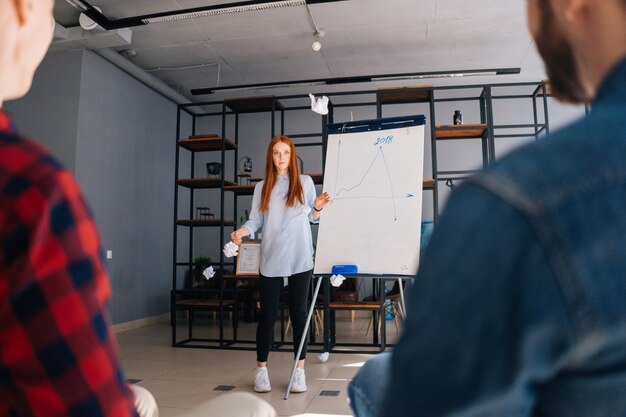 Lowangle-Aufnahme einer fröhlichen jungen Geschäftsfrau, die die Präsentation auf dem Whiteboard beendet