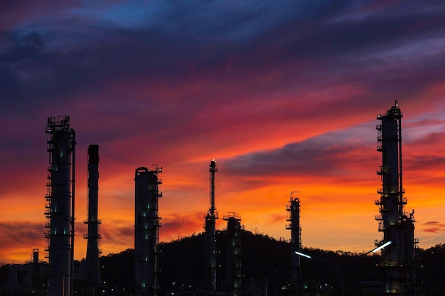 Ölraffinerie und Anlage und Turmsäule der petrochemischen Industrie in der Öl- und Gasindustrie mit wolkenrotem Himmel am Abendsonnenunterganghintergrund