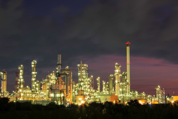 Ölraffinerie und Anlage und Turmsäule der petrochemischen Industrie in der Pipeline-Öl- und Gasindustrie mit Wolken, die den roten Himmel am Morgenhintergrund verlangsamen