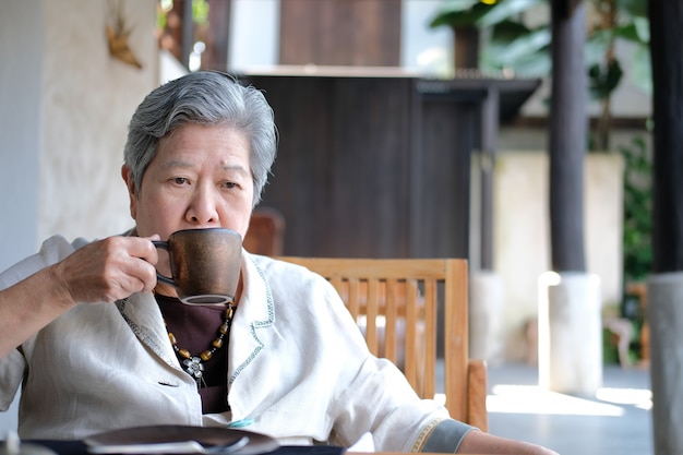 Ältere ältere Frau, die Kaffee-Tee trinkt