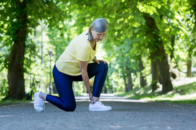 Ältere aktive Frau beim Joggen verletzte sich Bein und Knie grauhaariger Rentner in einem Sommerpark