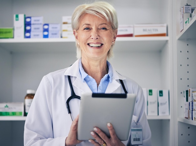 Ältere Apothekerin und Tablet-Datenporträt mit medizinischen Beständen und digitaler Telegesundheitsarbeit. Apotheken-Gesundheitsgeschäft und Forschung mit einer älteren Mitarbeiterin mit einem Lächeln und Informationen