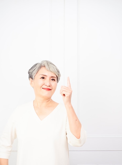 Ältere asiatische Frau, die oben 1 Finger zeigt.