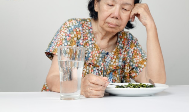 Ältere asiatische Frau gelangweilt vom Essen