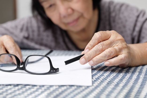 Ältere asiatische Frau repariert kaputte Brille