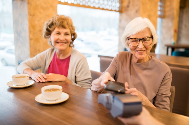 Ältere Damen, die mit Smartphone bezahlen