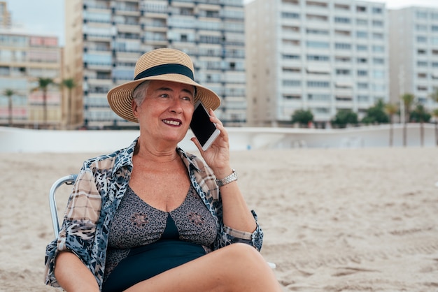 Ältere Frau am Strand am Handy