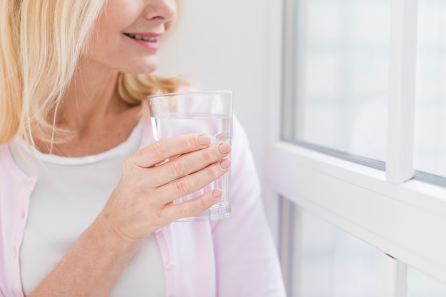 Ältere Frau der Nahaufnahme mit einem Glas Wasser