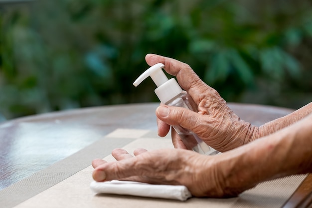 Ältere Frau, die Alkohol-Gel reinigende Hände anwendet, um vor Coronavirus covid-19 zu schützen