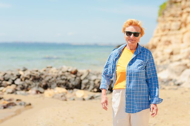 Ältere Frau, die am Strand in der Nähe des Meeres spazieren geht