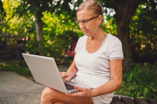 Ältere Frau, die an einem Laptop arbeitet