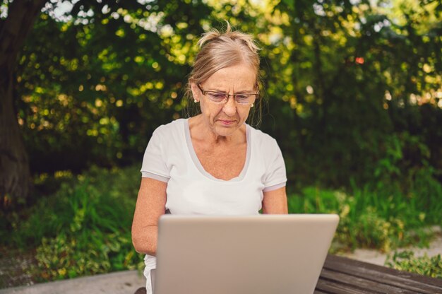 Ältere Frau, die an einem Laptop arbeitet