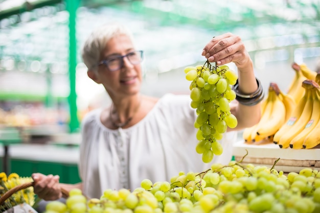 Ältere Frau, die auf Markt kauft