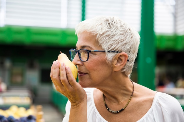 Ältere Frau, die auf Markt kauft