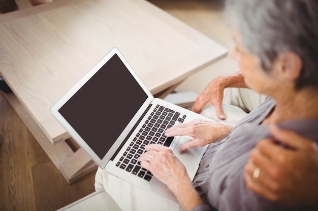 Ältere Frau, die auf Sofa sitzt und Laptop im Wohnzimmer verwendet