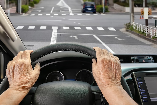 Ältere Frau, die ein Auto auf der Straße in der Stadt fährt.