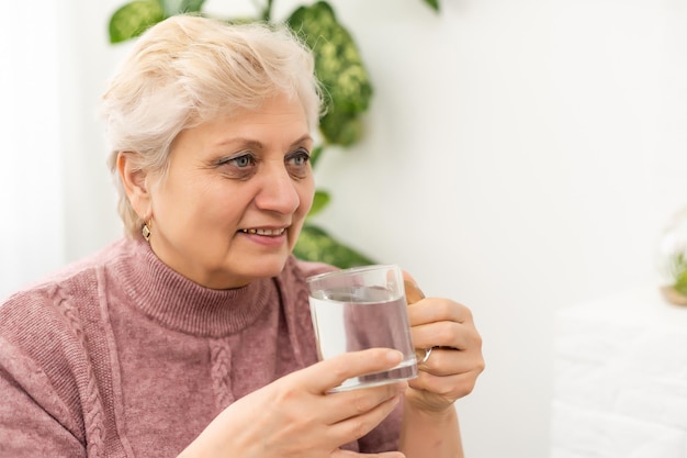 Ältere Frau, die ein Glas frisches Wasser trinkt.